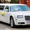 White wedding limousine on the road ornated with flowers