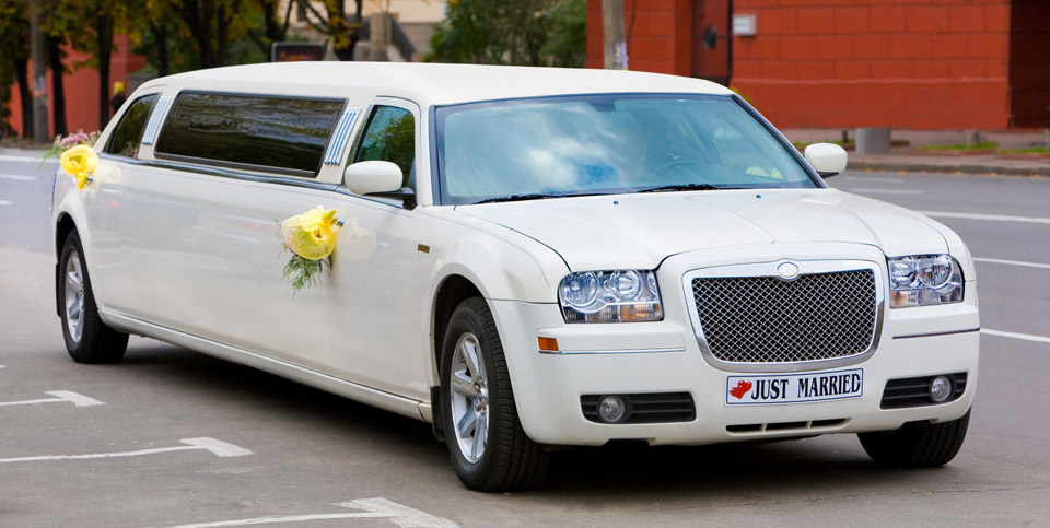 White wedding limousine on the road ornated with flowers